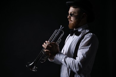 Professional musician with trumpet on black background