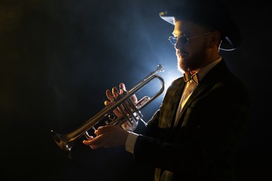 Professional musician playing trumpet on black background