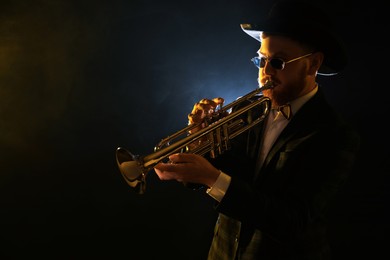 Photo of Professional musician playing trumpet on black background. Space for text
