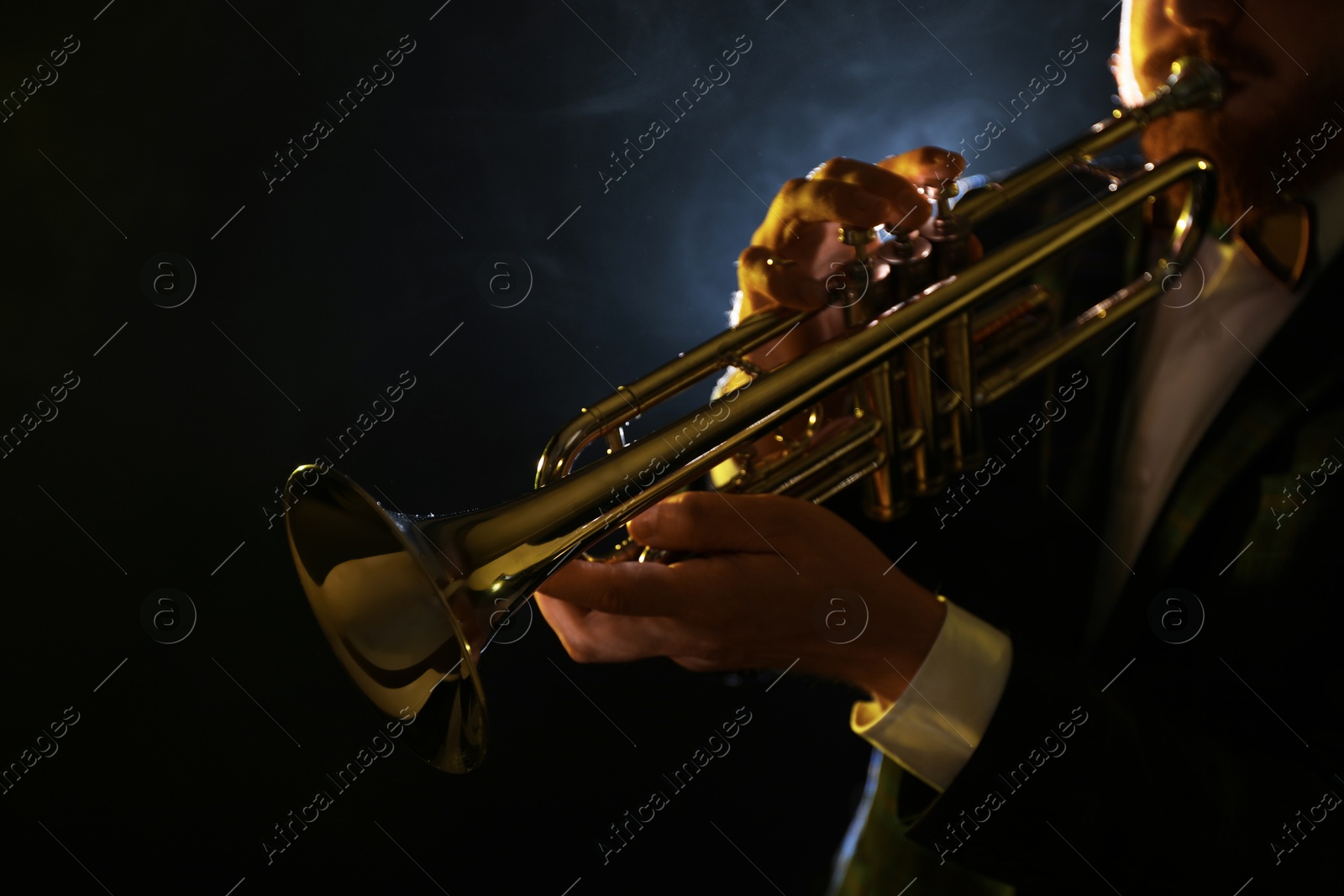 Photo of Professional musician playing trumpet on black background, closeup