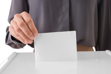 Photo of Woman putting her vote into ballot box against white background, closeup