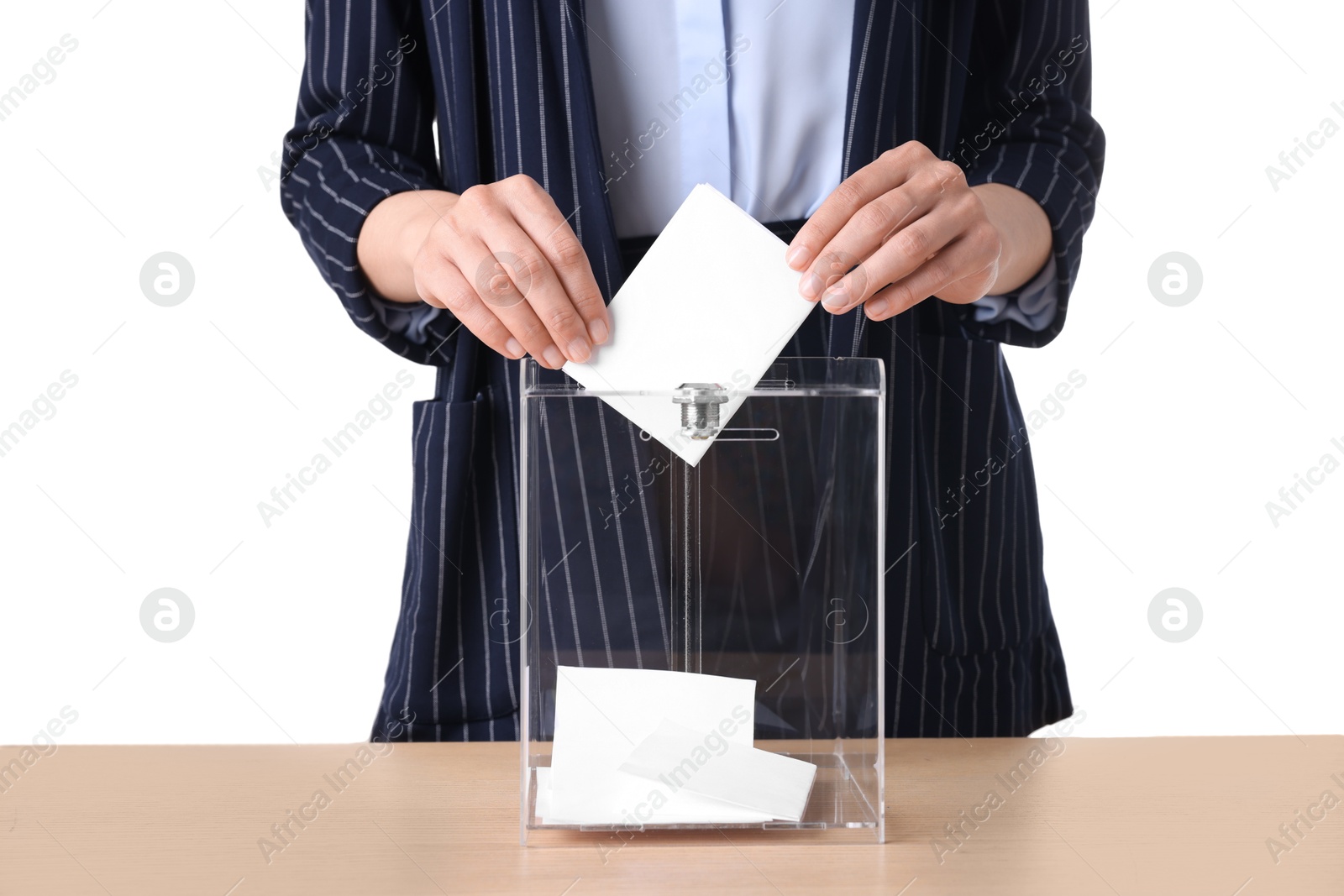 Photo of Woman putting her vote into ballot box at wooden table against white background, closeup