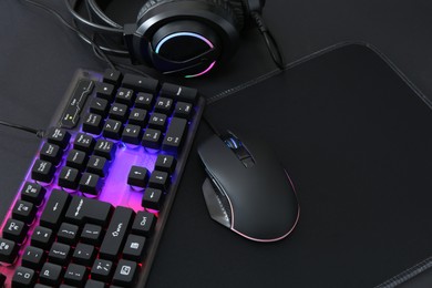 Photo of Computer mouse, RGB keyboard and headset on black background