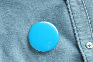 Photo of Blue button badge pinned on denim shirt, top view. Mockup for design