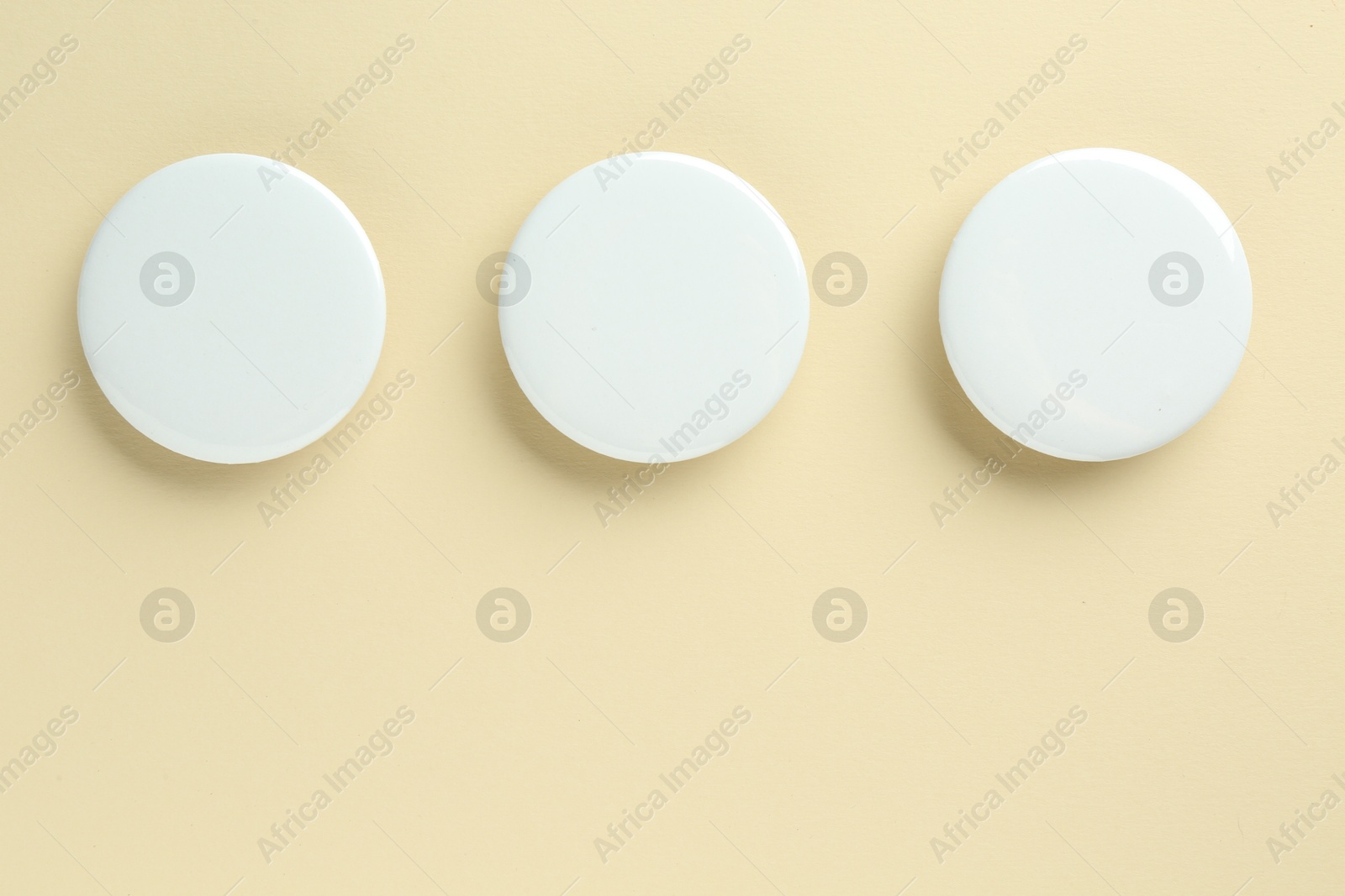 Photo of White button badges on beige background, flat lay. Mockup for design