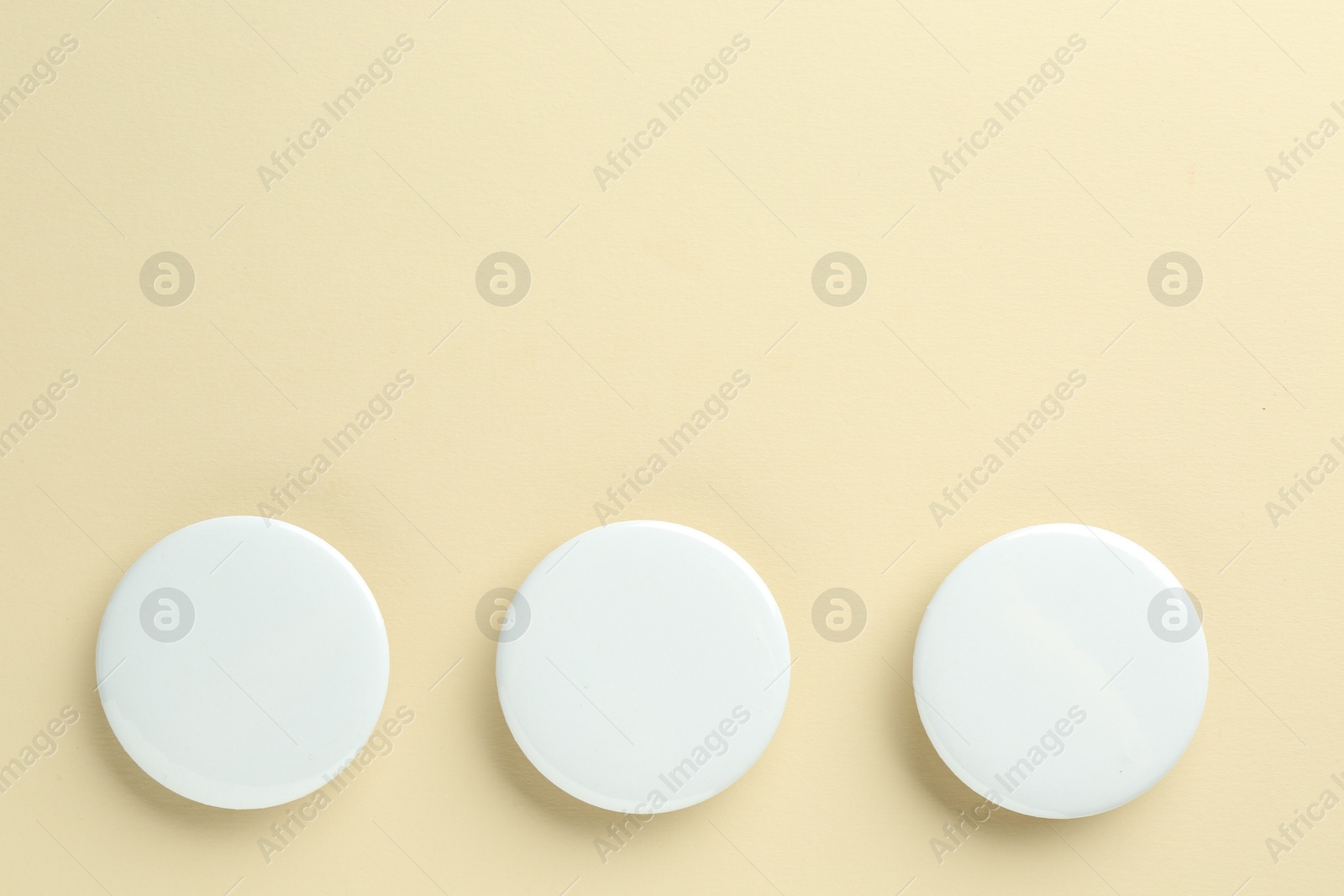 Photo of White button badges on beige background, flat lay. Mockup for design