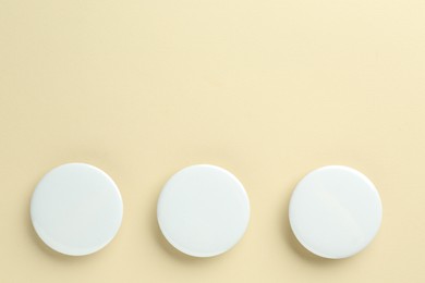 White button badges on beige background, flat lay. Mockup for design