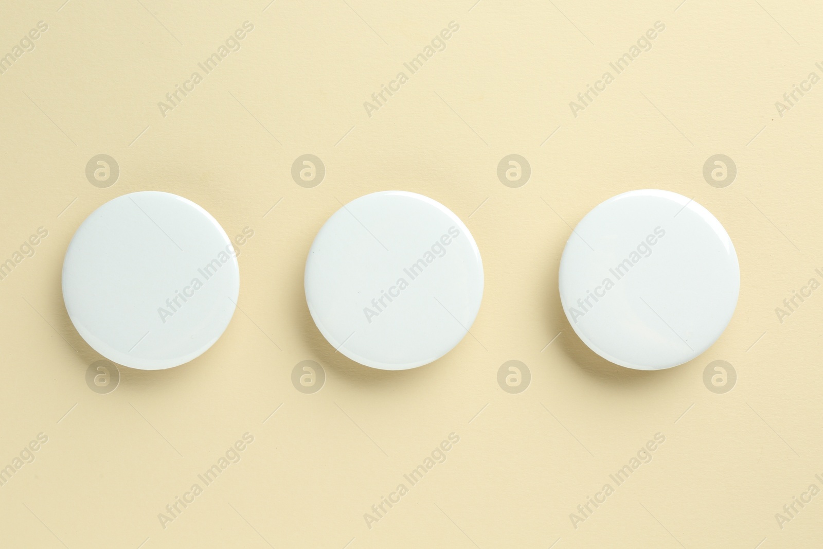 Photo of White button badges on beige background, flat lay. Mockup for design