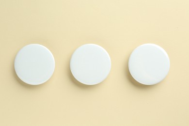 Photo of White button badges on beige background, flat lay. Mockup for design