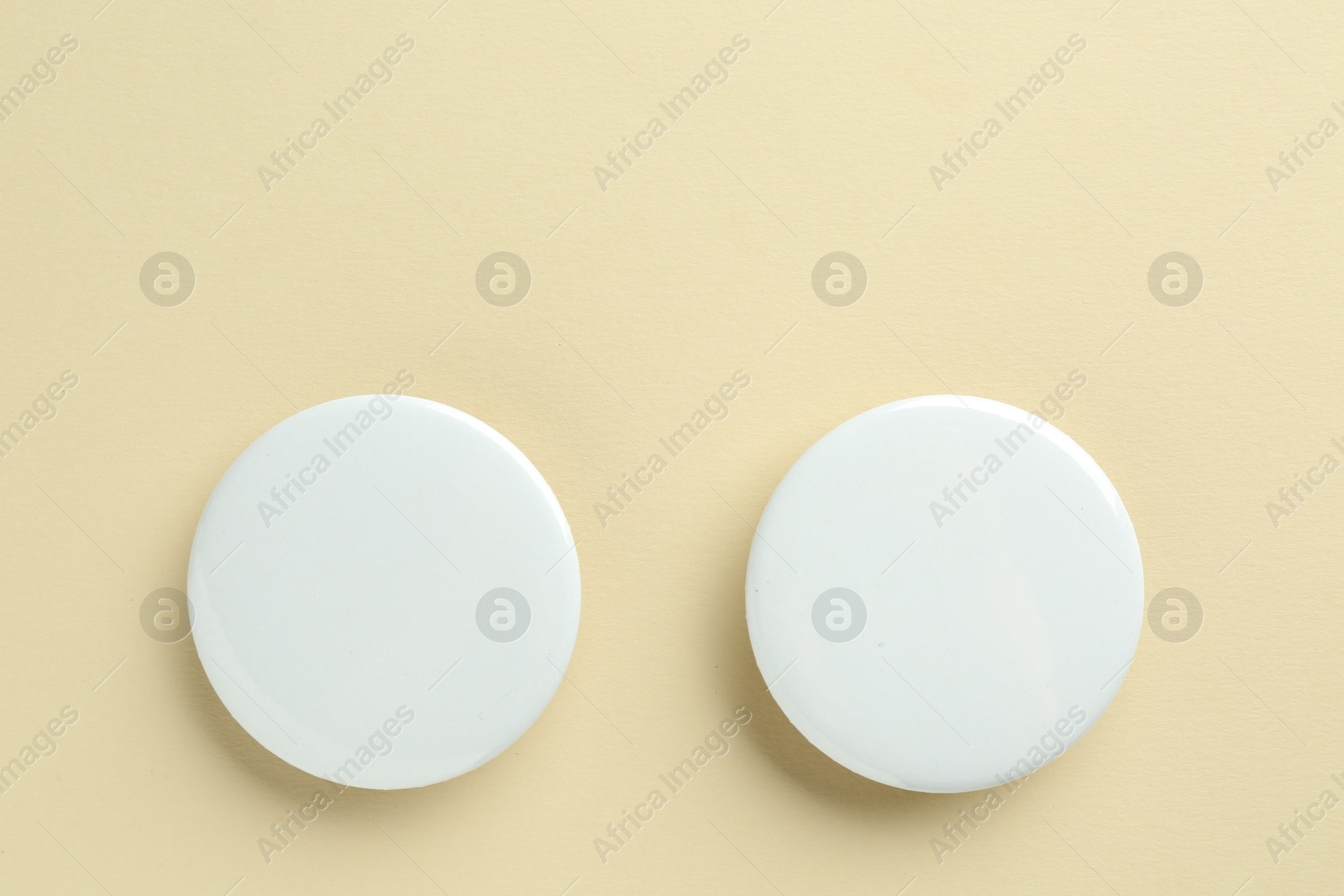 Photo of White button badges on beige background, flat lay. Mockup for design