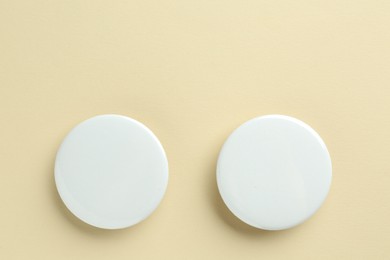 White button badges on beige background, flat lay. Mockup for design