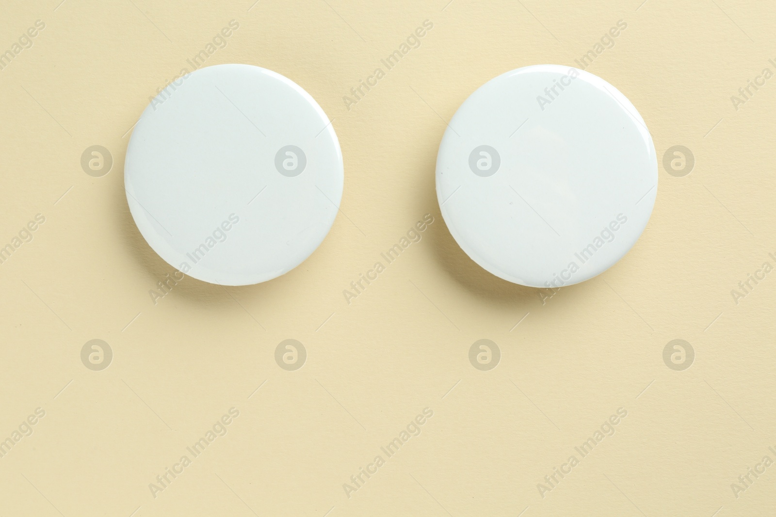 Photo of White button badges on beige background, flat lay. Mockup for design