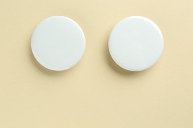 White button badges on beige background, flat lay. Mockup for design