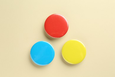 Colorful button badges on beige background, flat lay. Mockup for design