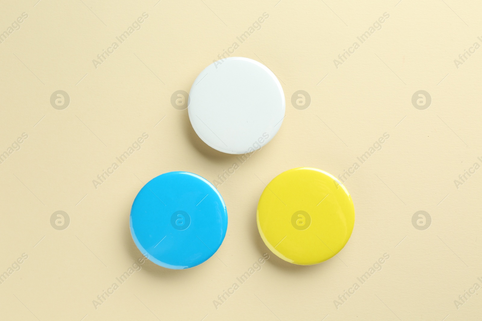 Photo of Colorful button badges on beige background, flat lay. Mockup for design