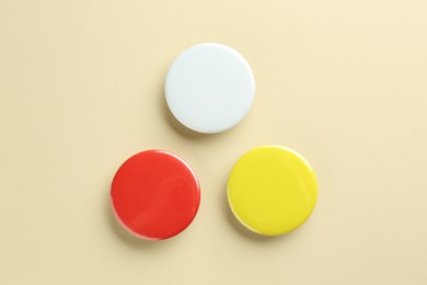 Colorful button badges on beige background, flat lay. Mockup for design