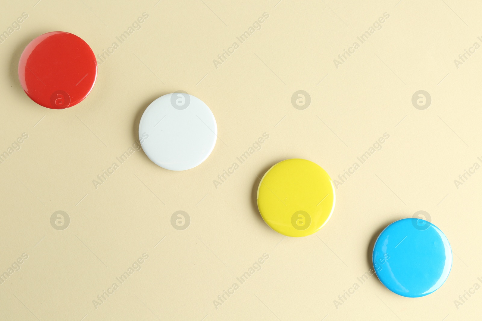 Photo of Colorful button badges on beige background, flat lay. Mockup for design