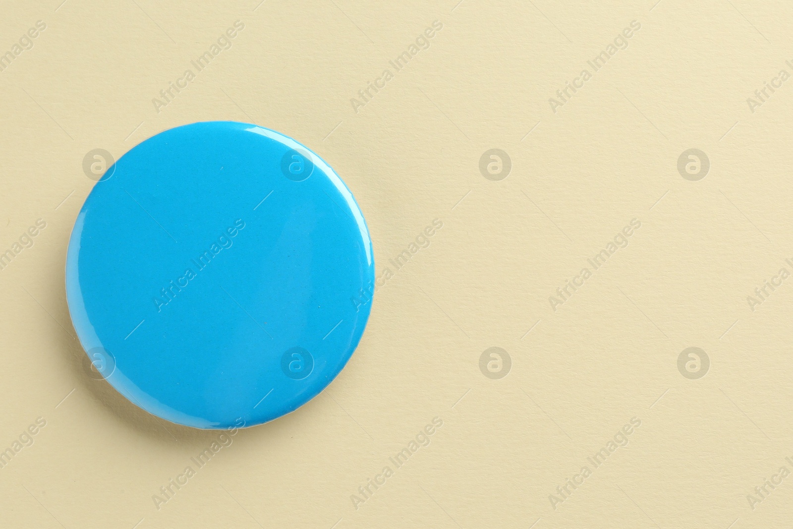 Photo of Blue button badge on beige background, top view. Mockup for design