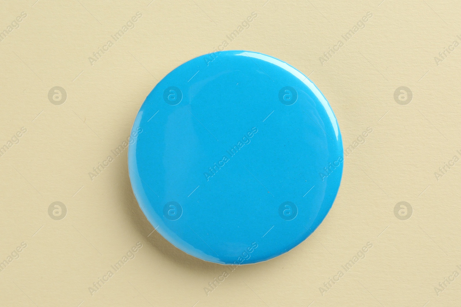 Photo of Blue button badge on beige background, top view. Mockup for design