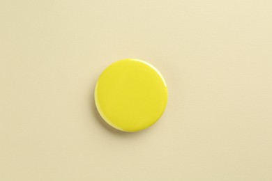 Photo of Yellow button badge on beige background, top view. Mockup for design