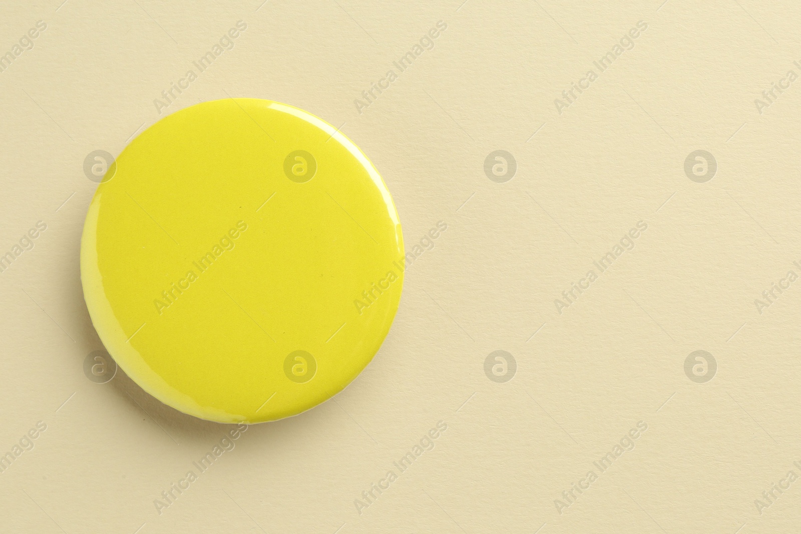 Photo of Yellow button badge on beige background, top view. Mockup for design