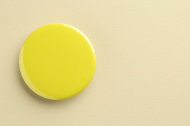 Photo of Yellow button badge on beige background, top view. Mockup for design