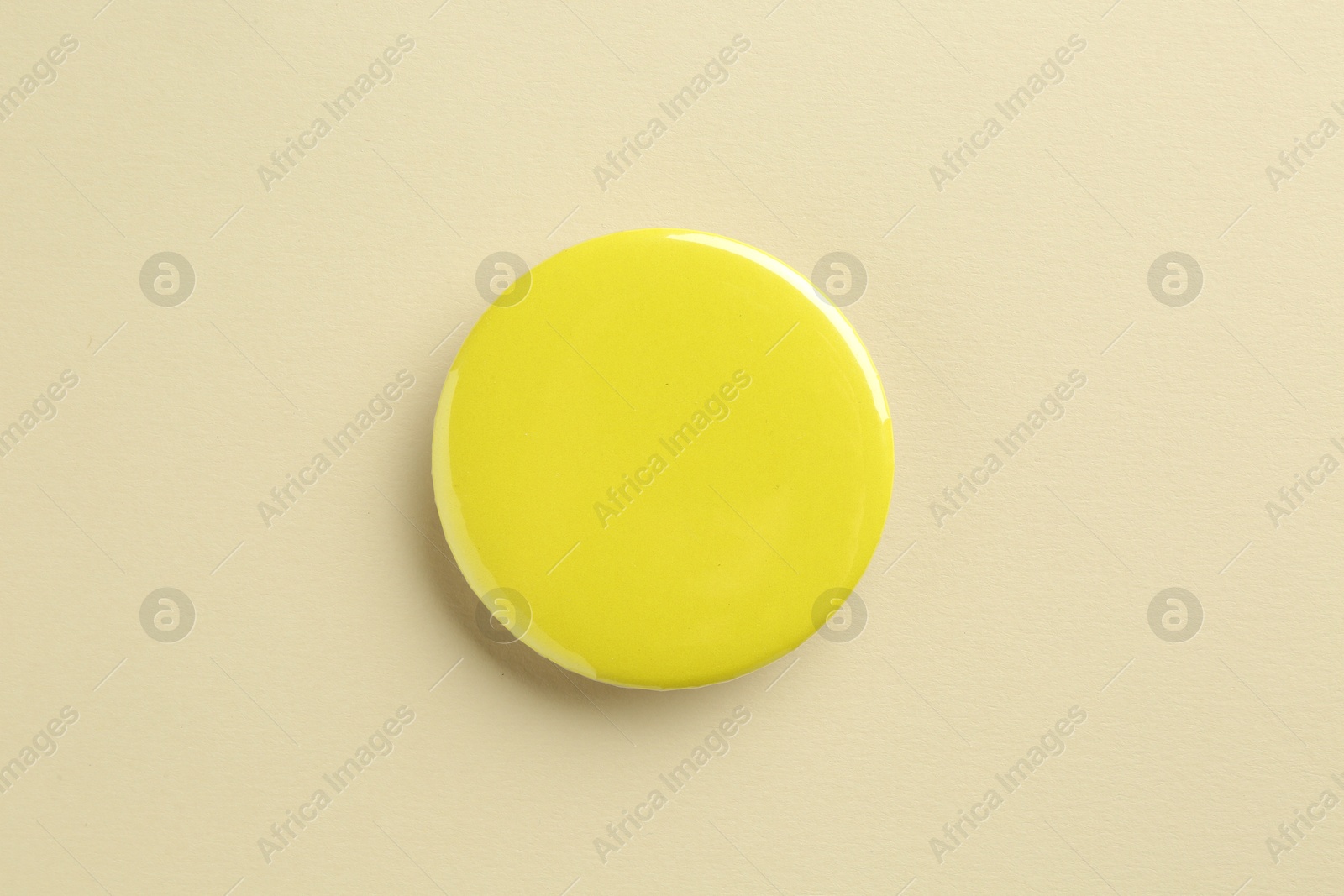 Photo of Yellow button badge on beige background, top view. Mockup for design