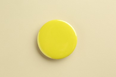 Photo of Yellow button badge on beige background, top view. Mockup for design