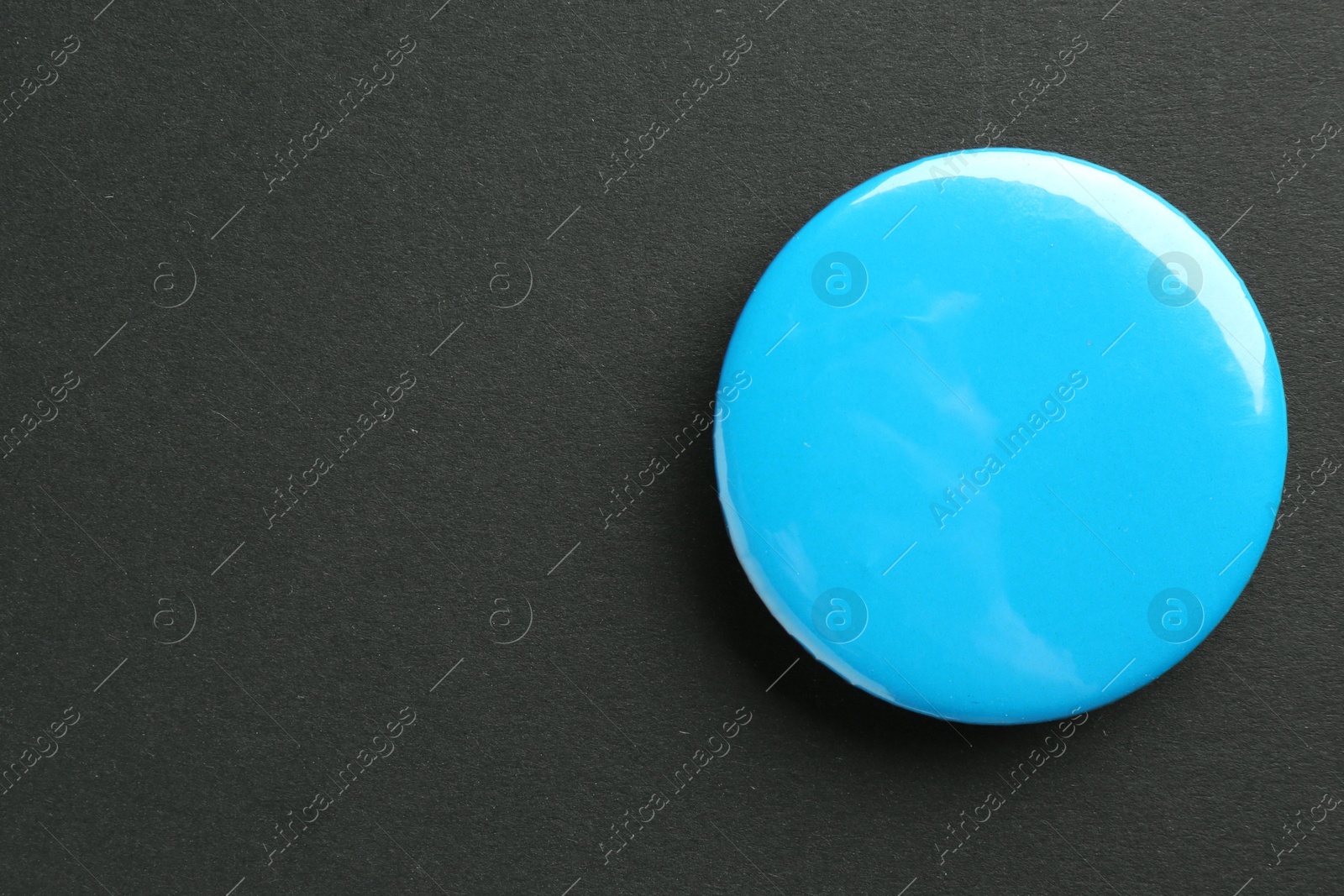 Photo of Blue button badge on black background, top view. Mockup for design