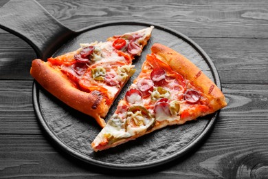 Photo of Board with pieces of delicious pizza Diablo on black wooden table, closeup