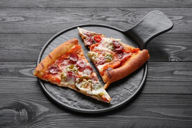 Photo of Board with pieces of delicious pizza Diablo on black wooden table