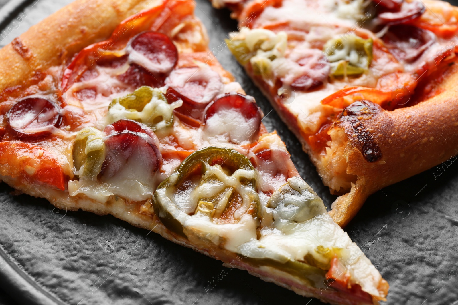 Photo of Pieces of delicious pizza Diablo on textured board, closeup