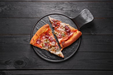 Photo of Board with pieces of delicious pizza Diablo on black wooden table, top view