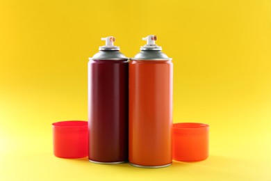 Two spray paint cans on yellow background