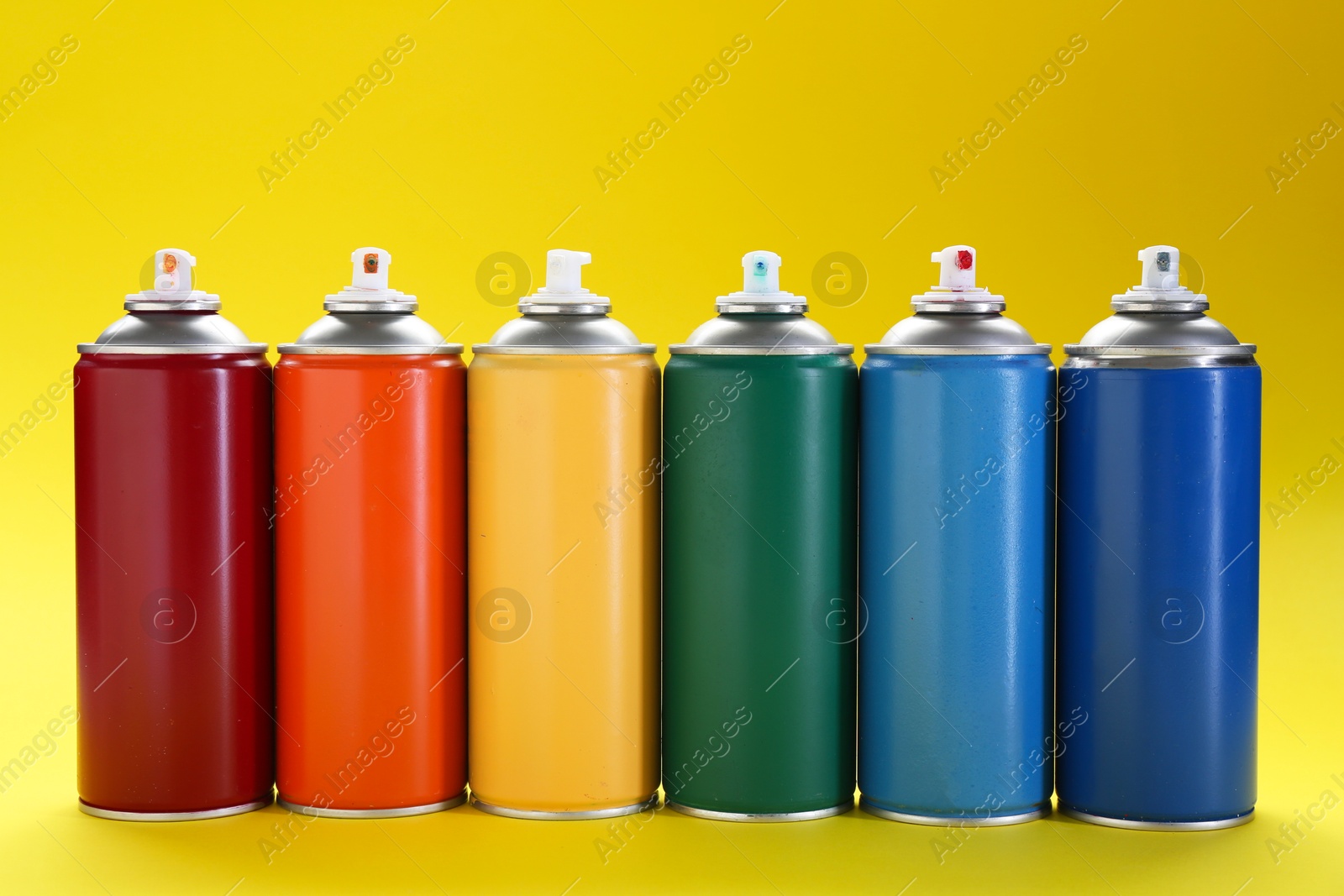 Photo of Many spray paint cans on yellow background