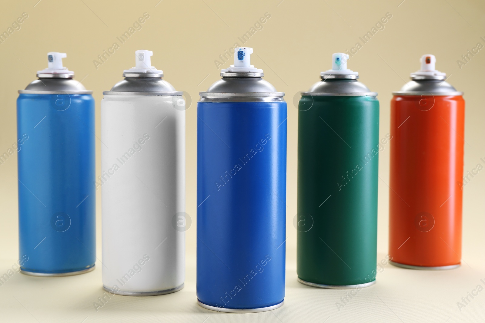 Photo of Many spray paint cans on beige background