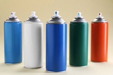 Photo of Many spray paint cans on beige background