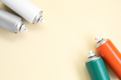 Many spray paint cans on beige background, top view. Space for text