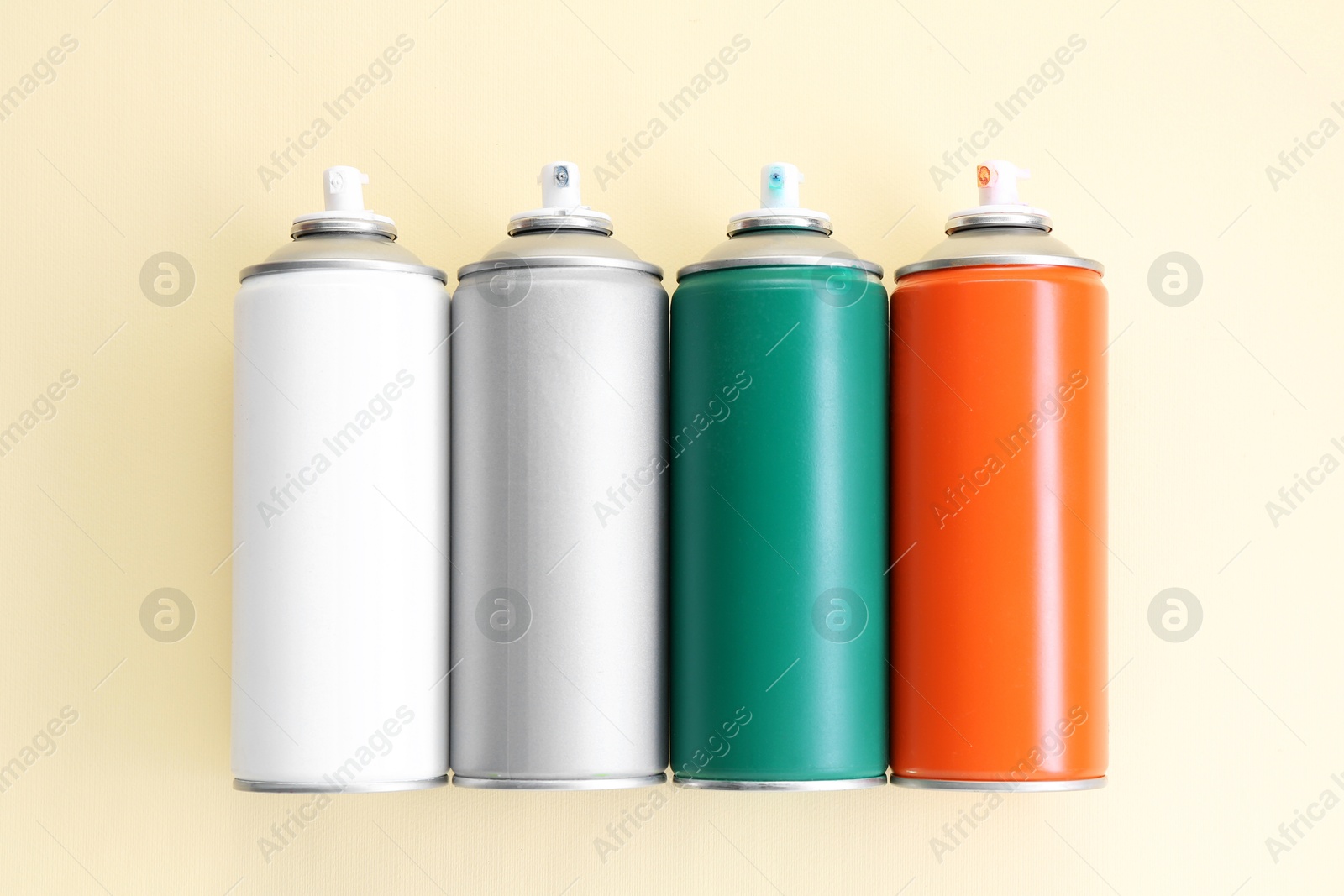 Photo of Many spray paint cans on beige background, top view