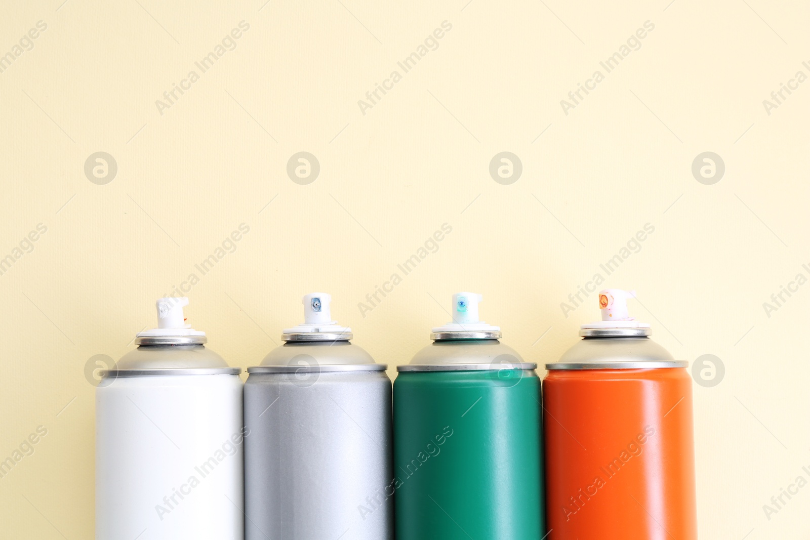 Photo of Many spray paint cans on beige background, top view. Space for text