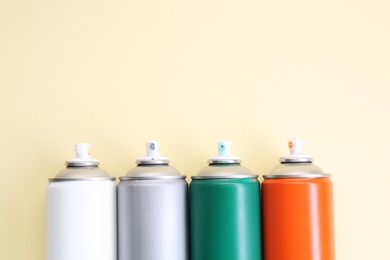 Many spray paint cans on beige background, top view. Space for text