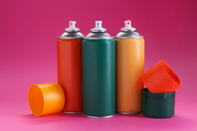 Photo of Many spray paint cans on pink background