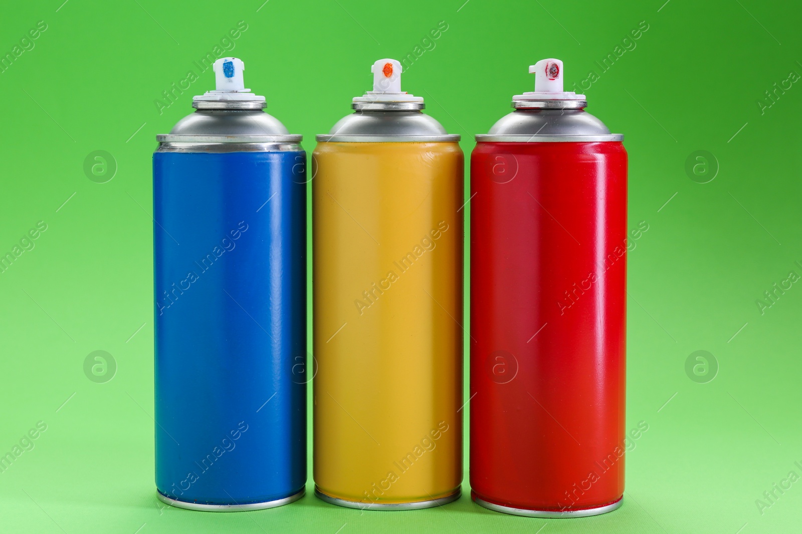 Photo of Many spray paint cans on green background