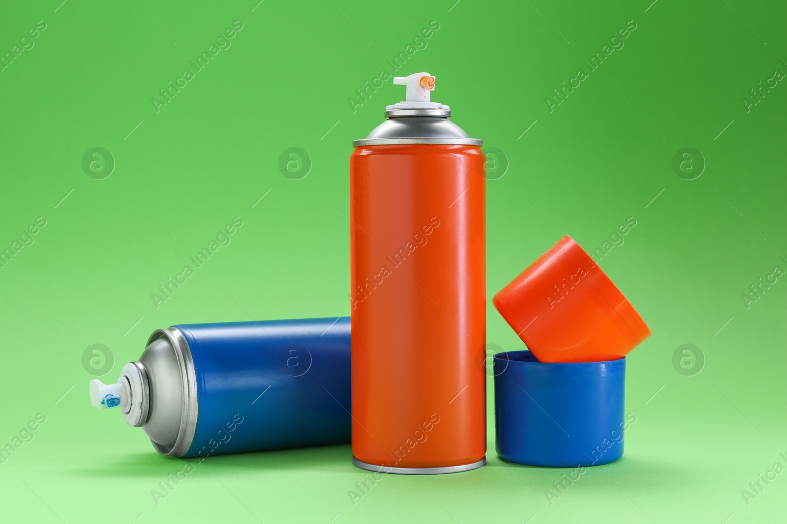 Photo of Two spray paint cans on green background