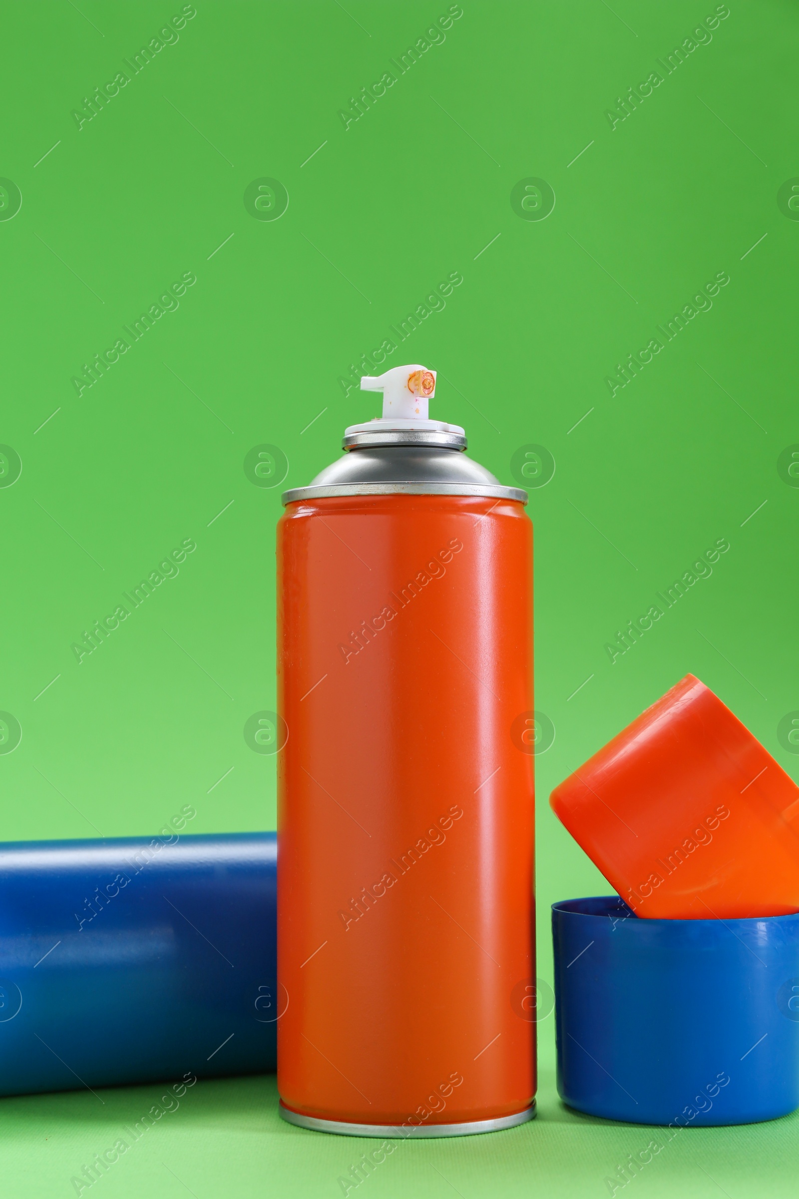 Photo of Two spray paint cans on green background