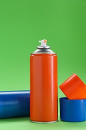 Two spray paint cans on green background