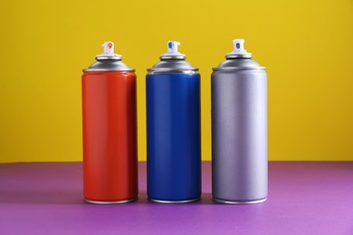 Photo of Many spray paint cans on color background