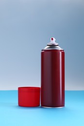 Red spray paint can on color background