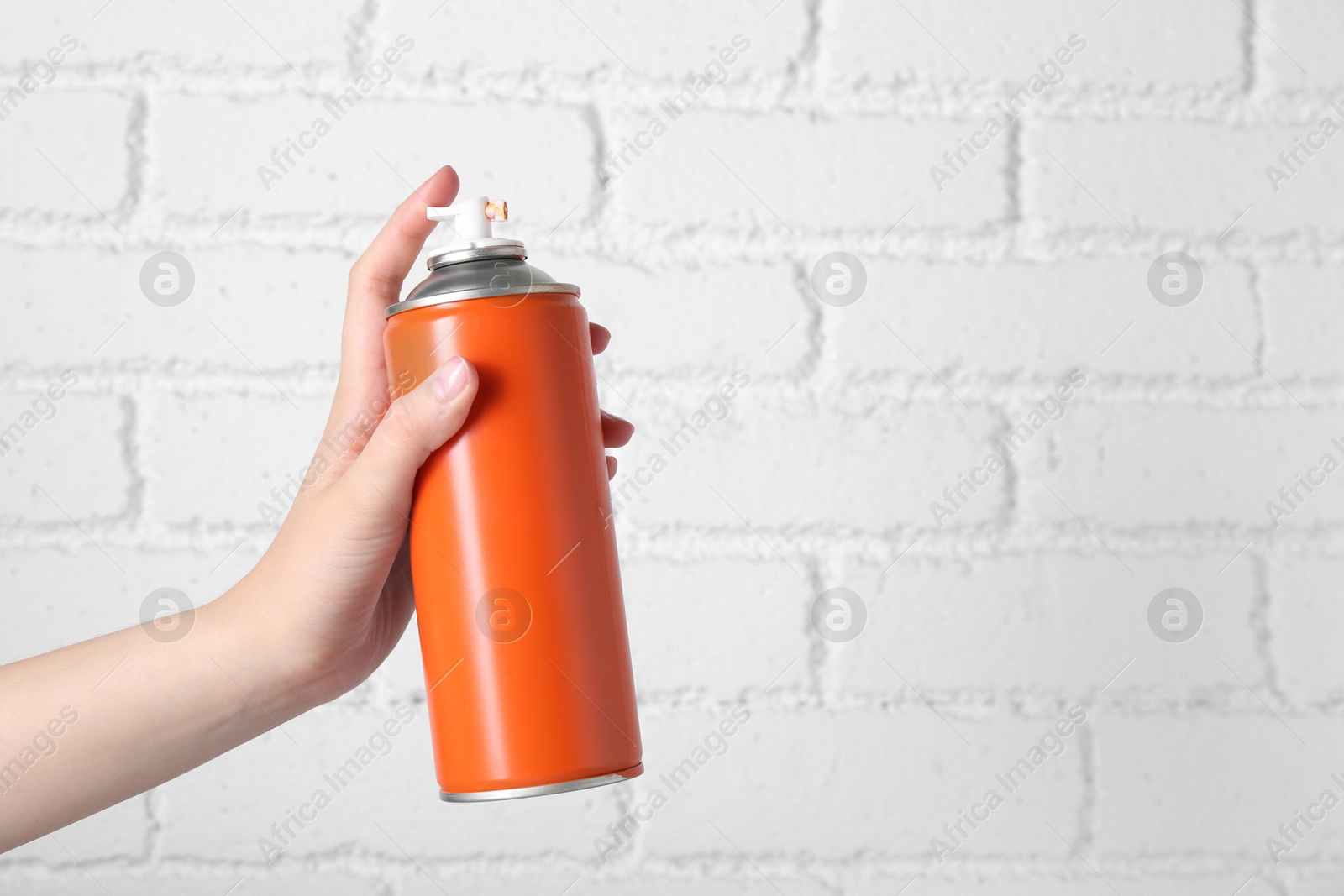 Photo of Woman with can of spray paint near white brick wall, closeup. Space for text