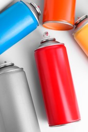 Photo of Cans of spray paint on white background, flat lay